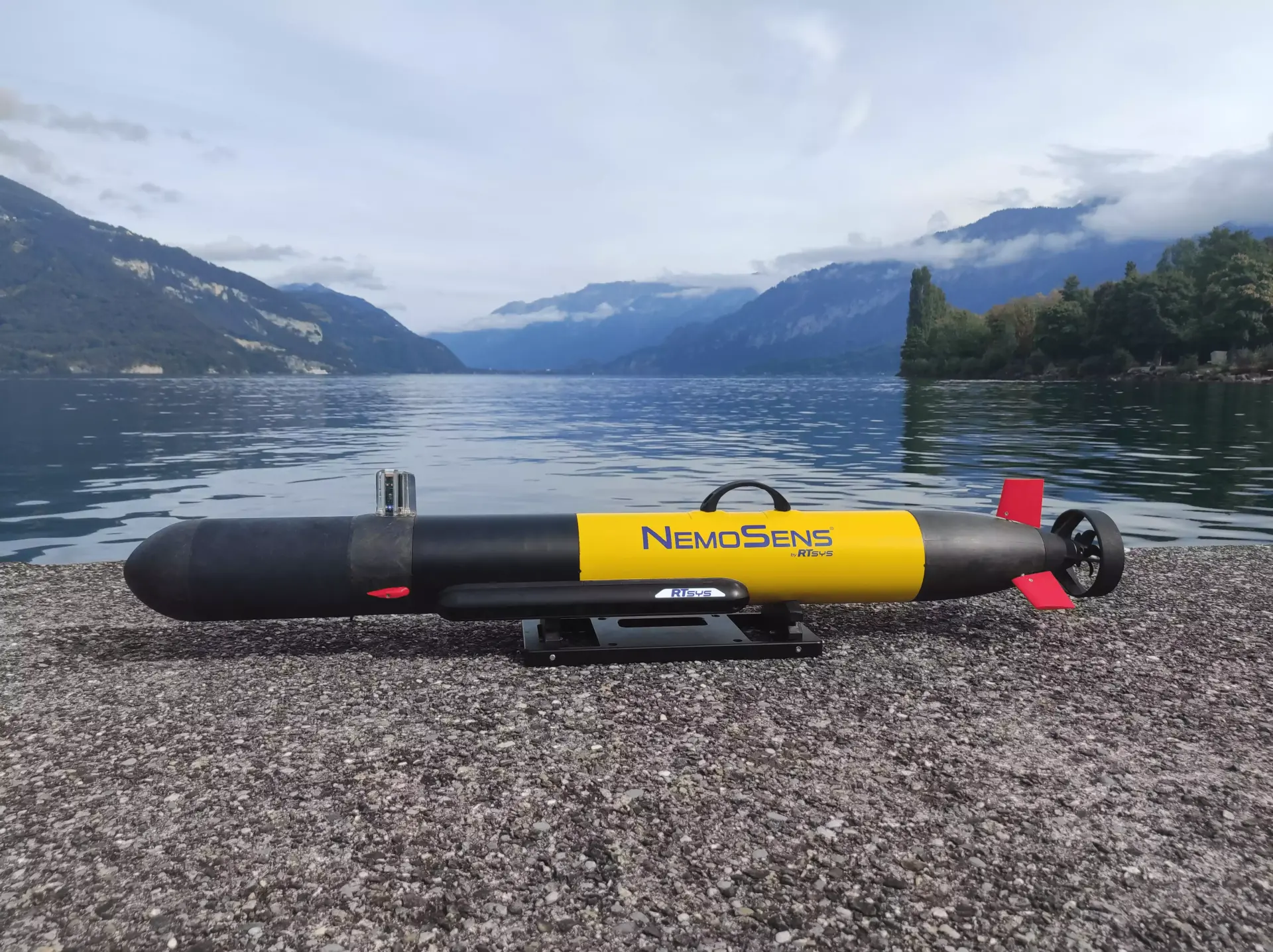 The NemoSens AUV on shore by the mountains.